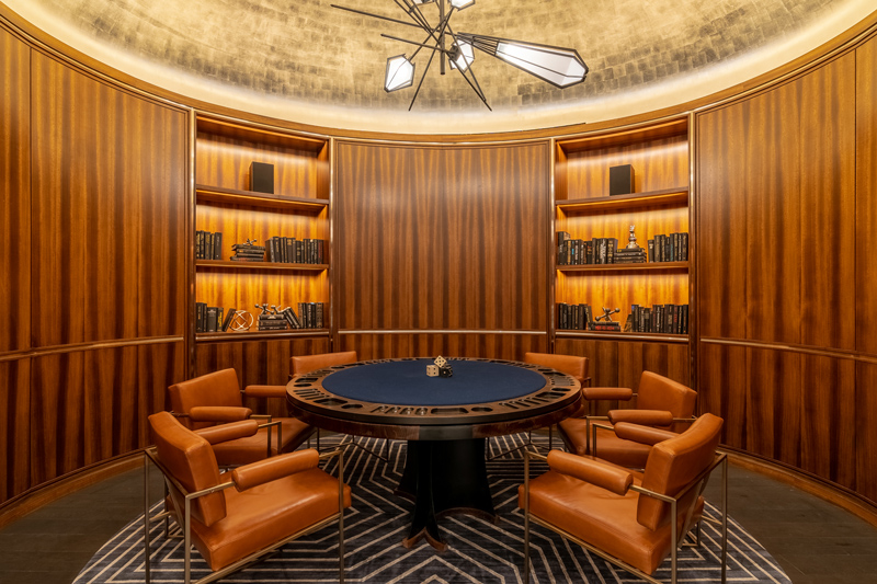 A golf-leaf dome ceiling disperses the diffused warm LED light into the wood paneled poker room