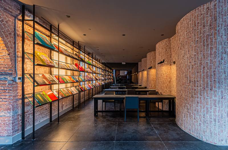 A wall-length magazine stand is lit with warm LED lighting accents