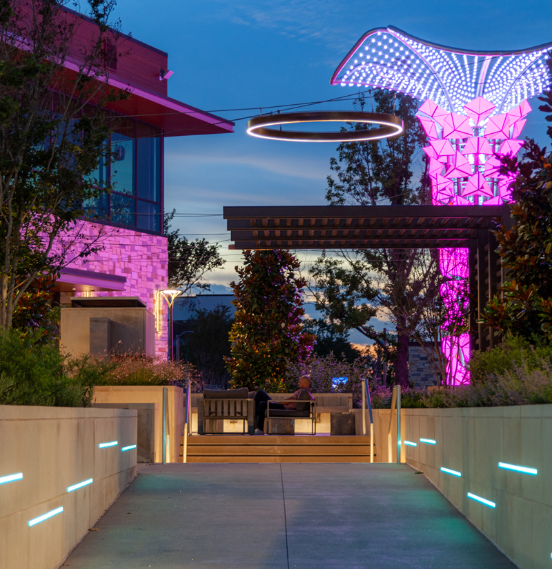 Colorful LED lights illuminate the walkway and architectural element in Texas